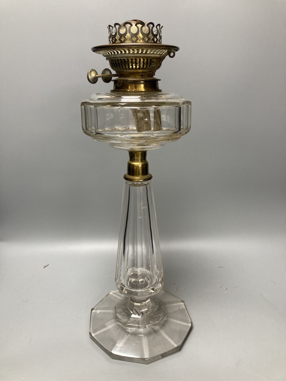 A late 19th century cut glass oil lamp with floral embossed shade, 61cm high including shade